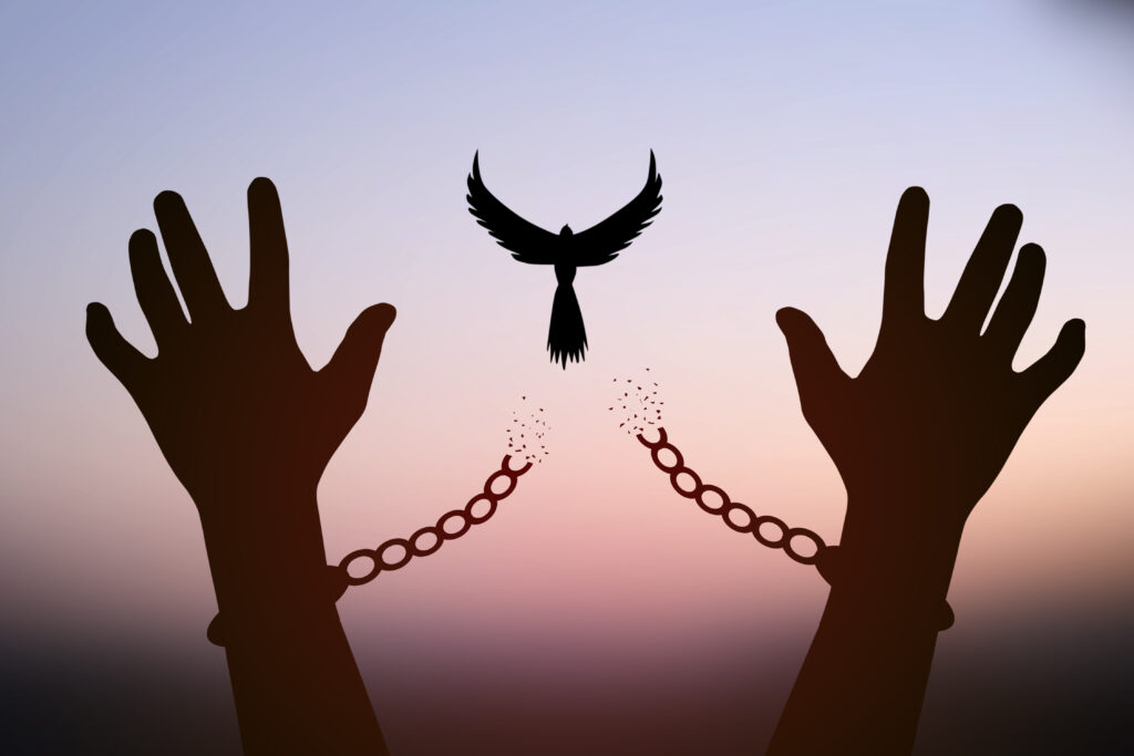 Freedom concept. The top dove leaves the broken chain from the prisoner's arm.
