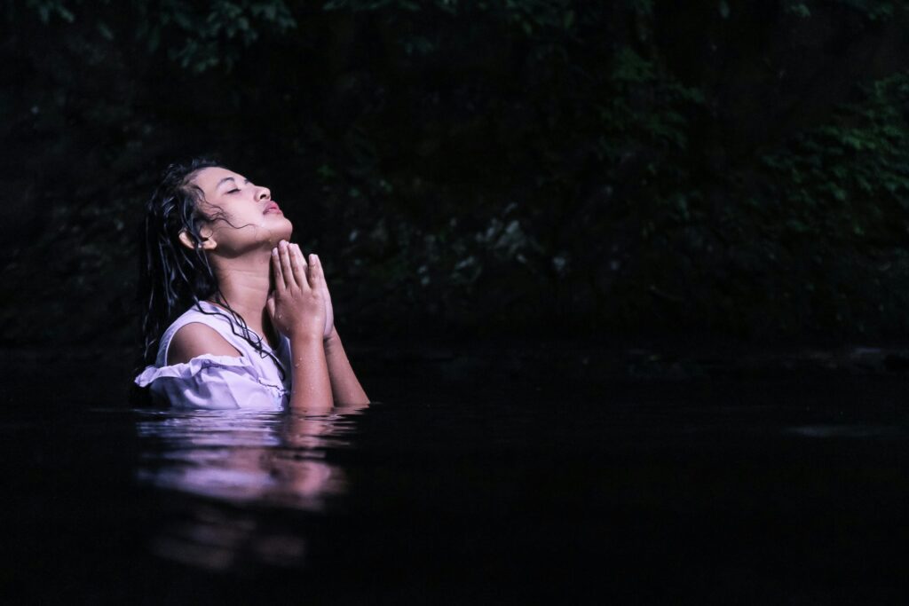 Woman praying while standing in water.